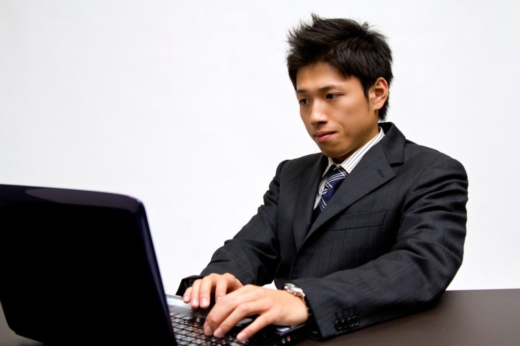 パソコン情報を整理ている男性の画像